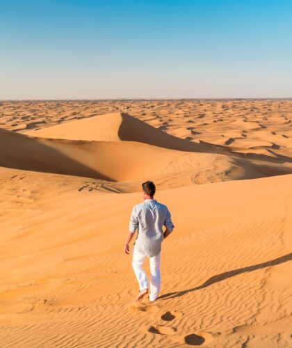 Dubai desert sand dunes, young men walking at the sand dunes of Dubai during a desert safari