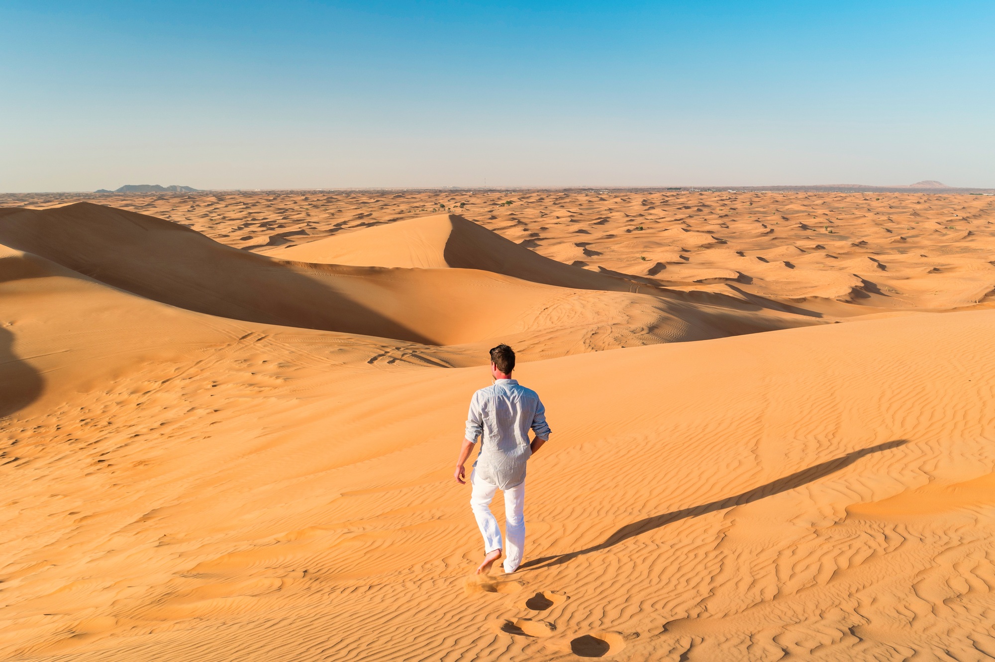 Dubai desert sand dunes, young men walking at the sand dunes of Dubai during a desert safari