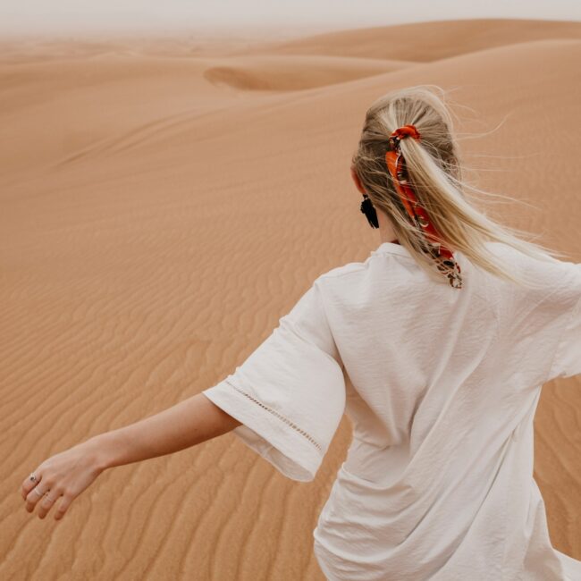 United Arab Emirates, Dubai, Lahbab Desert, woman walking in desert landscape