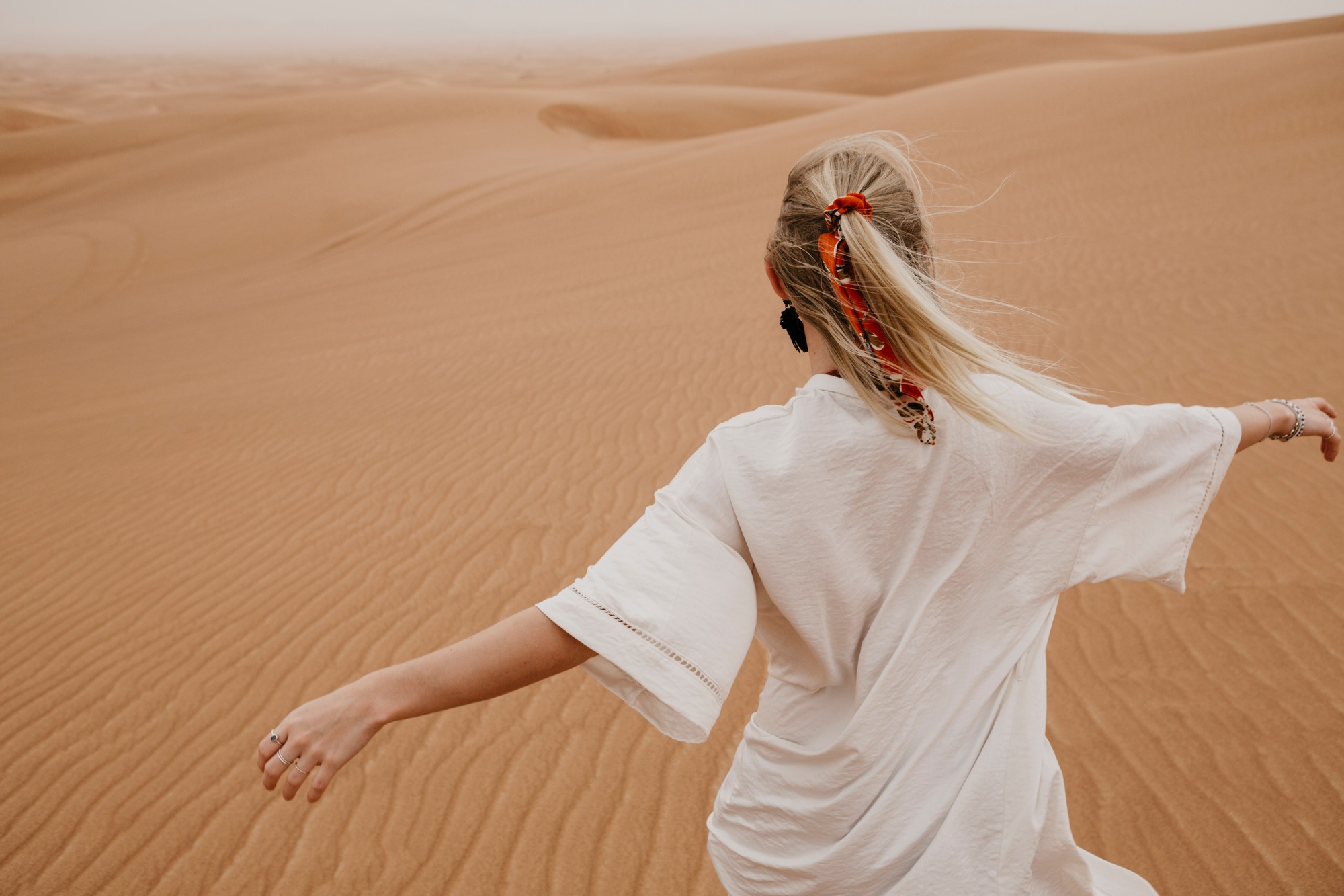 United Arab Emirates, Dubai, Lahbab Desert, woman walking in desert landscape